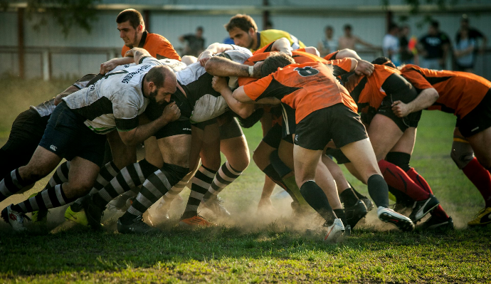 A group of rugby players in a scrum on a grassy field